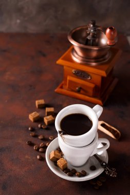 Bir fincan sıcak kahve kahve çekirdekleri, Kahve değirmeni ve kahve çekirdekleri çanta taş kahverengi bir arka plan üzerinde buğulaması. Kopya alanı