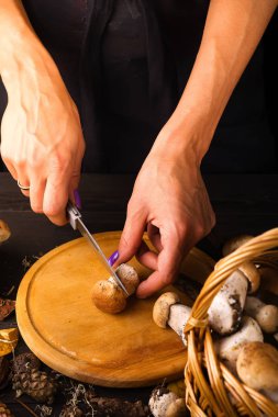 Erkek kesilmiş taze orman mantar bir ahşap tahta üzerinde ahşap arka plan üzerinde karanlık eller. Rustik tarzı, doğal gün ışığı. Yakın çekim