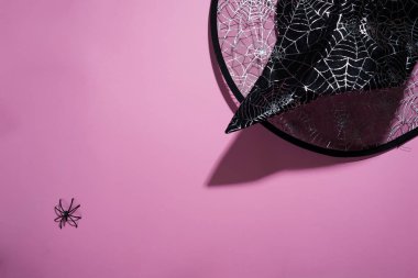 Kara cadı şapka ile pembe bir arka plan üzerinde siyah örümcek örümcek ağları, kopya alanı ile üst görünümden bir deseni ile. Cadılar Bayramı arka plan