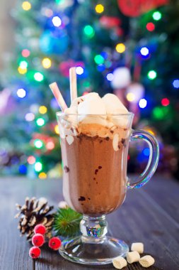 Cam fincan sıcak kakao çam dallar ile mini marshmallow ile bokeh güzel Noel ışıkları ile rustik bir arka plan. Kahve de olabilir.