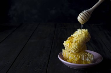 kopya alanı kayrak bir zemin üzerine seramik bir tabakta bal damlayan bir ahşap kepçe ile taze petek parçaları