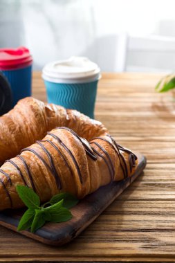 ahşap masa üzerinde kahve fincanı ile taze pişmiş kruvasanlar 