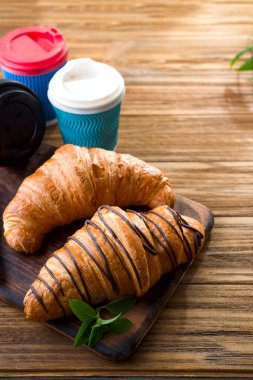 ahşap masa üzerinde kahve fincanı ile taze pişmiş kruvasanlar 