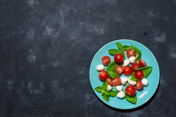 신선한 이탈리아 caprese 복사 공간 어두운 돌 배경에 파란색 접시에 토마토와 모 짜 렐 라 샐러드, 평면 배치 — 스톡 사진