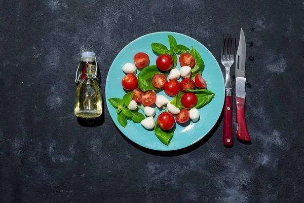 Insalata caprese fresca italiana con mozzarella e pomodori su fondo pietra scura con spazio per copiare, posa piatta — Foto Stock