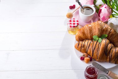 taze pişmiş kruvasan reçel ile dekore edilmiş kahvaltı ve çikolata, çiçek ile bir mutfak ahşap tablo alanı Kopyala