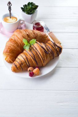 taze pişmiş kruvasan reçel ile dekore edilmiş kahvaltı ve kopya alanı ile bir mutfak ahşap tablo çikolata, çay veya kahve, çiçekler