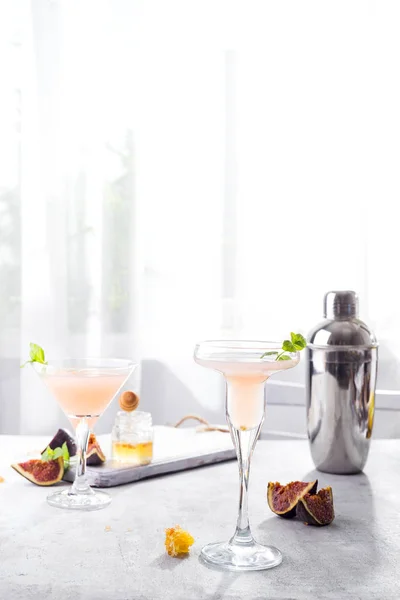 Bellini cocktail with peach and figs, honey on light background over windows, copy space