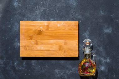 metni, düz ahşap tahtası siyah taş zemin üzerine kırmızı biber ile cam şişe zeytinyağı yatıyordu