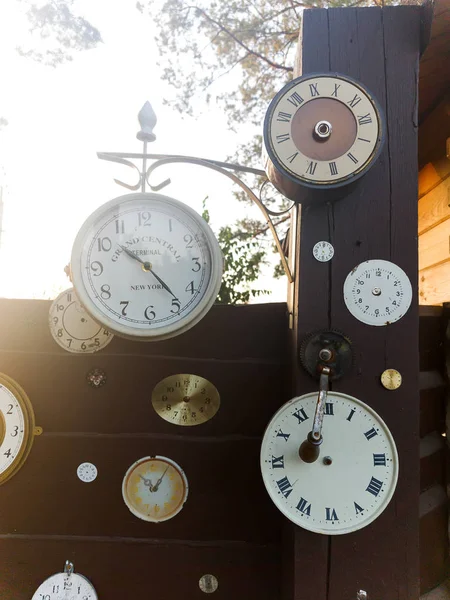 Συλλογή vintage ρολόι που κρέμεται από ένα παλιό ξύλινο τείχος σχετικά με τους εξωτερικούς χώρους με ηλιοφάνεια — Φωτογραφία Αρχείου