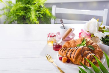 taze pişmiş kruvasan ve kahve üzerinde arka planı gri kayrak izole çikolata sosu ve palm izni ile dekore edilmiş.