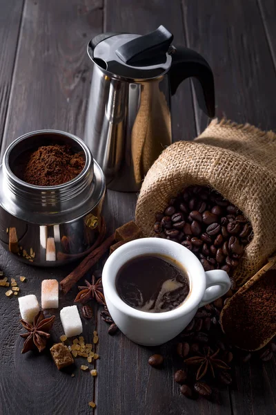 Café moulu est rempli d'une cafetière geyser et tasse de café épices esprit sur une table en bois sur un fond en bois sombre, espace de copie — Photo