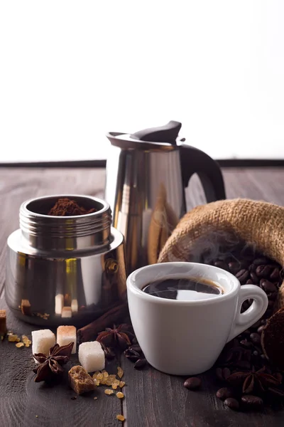 Gejzír kávéfőző és egy csésze kávé wit fűszerek egy fából készült asztal sötét fából készült háttér előtt, másol hely tele őrölt kávé — Stock Fotó