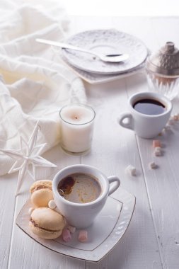Lezzetli tatlı macarons ve kahve fincanı Beyaz ahşap zemin üzerinde. Noel kavramı tembel sabah, sıcak kış ruh hali