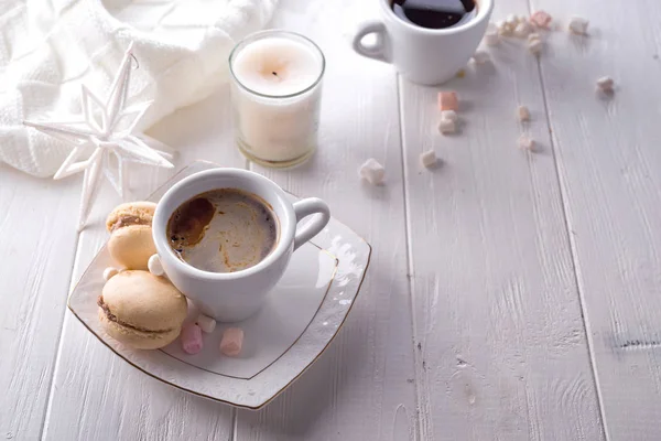 Lezzetli tatlı macarons ve kahve fincanı Beyaz ahşap zemin üzerinde. Noel kavramı tembel sabah, sıcak kış ruh hali