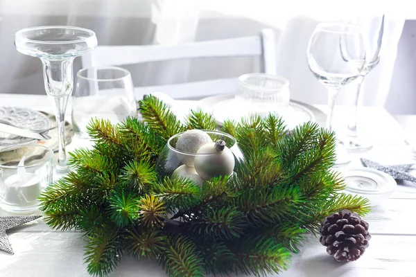 Corona de Navidad con juguetes en la mesa con mesa de Navidad de plata Ajuste con decoraciones de Navidad por encima de la ventana de luz —  Fotos de Stock