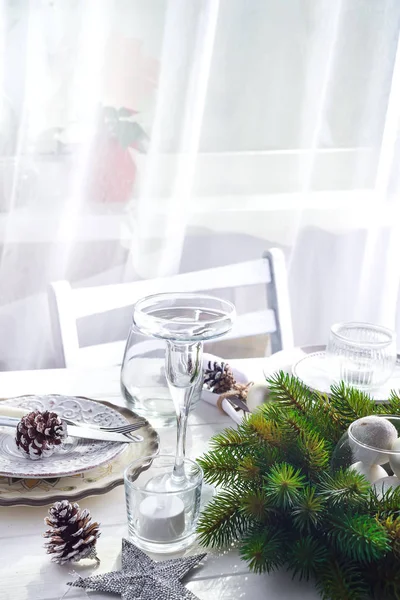 Corona de Navidad con juguetes en la mesa con mesa de Navidad de plata Ajuste con decoraciones de Navidad por encima de la ventana de luz —  Fotos de Stock