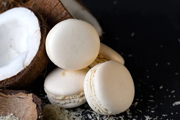 Metades de coco com macaroons brancos no fundo escuro conceito criativo mínimo . — Fotografia de Stock