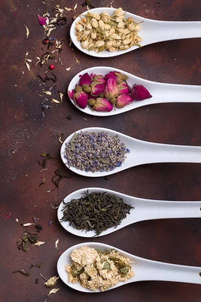 Cucharas de cerámica con hierbas secas, capullos de flores y hojas de té sobre fondo de piedra, vista superior , —  Fotos de Stock