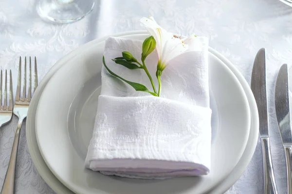 Piatto a tavola con tovagliolo e fiore su bianco, primo piano — Foto Stock