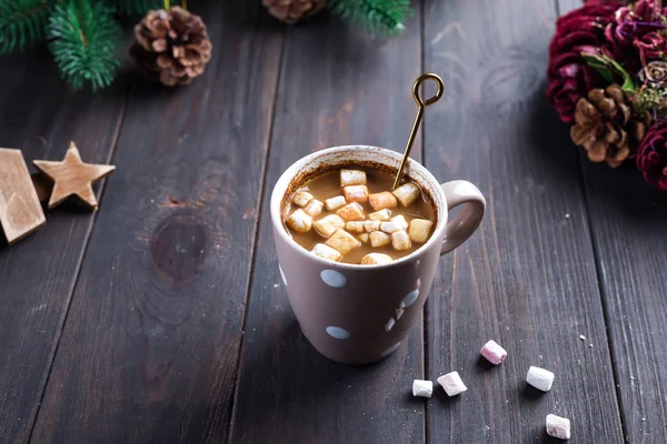 Cappuccino caldo con marshmallow in tazza di ceramica con miele e bastoncino di miele di metallo su fondo scuro in legno con rami di albero di Natale e decorazioni natalizie — Foto Stock
