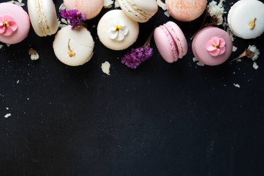 Renkli macarons siyah taş zemin üzerine. Kopya alanı ile üstten görünüm.