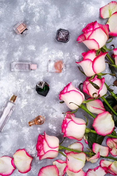 Kompozycja kwiatowy kadru z róż i wiele różnych perfum butelek na kamienne podłoże. Widok płaski świeckich, top. Walentynki — Zdjęcie stockowe
