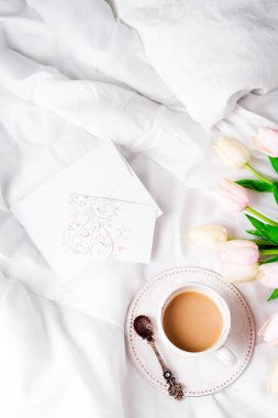 Lale çiçek fincan kahve ve posta kartı düz ile kavramı kompozisyon sabah Sevgililer yatakta yatıyordu. Üstten görünüm