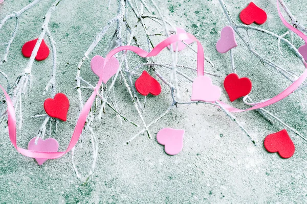 Rami nella neve con cuori rosa e rossi su uno sfondo concreto con spazio per il testo. Concetto di San Valentino — Foto Stock