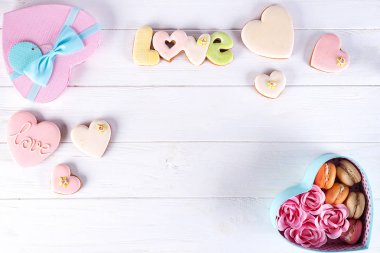 Kalpler çerezleri ve kutusunda macaroons. Festival yuvarlak mavi kutu kurabiye ve gül Beyaz ahşap zemin üzerinde düz kopya alanı ile yatıyordu.