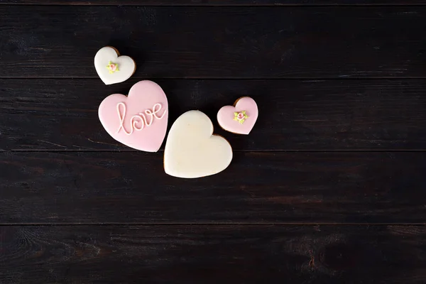 Bonbons le jour de la Saint-Valentin. Cookies en forme de coeur et avec lettrage Amour sur fond bois foncé vue du dessus copier l'espace — Photo