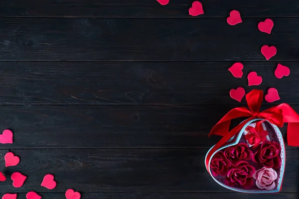 Kytice a Valentines pozadí s červenými srdci ve tvaru růže v dárkovém balení na tmavé dřevěné pozadí, plochá ležela kopie prostor — Stock fotografie