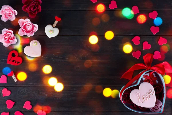Sladkosti na Valentýna. Sušenky ve tvaru srdce a nápisy láska, červené srdce ve tvaru a kytice růže v dárkovém balení na tmavé dřevěné pozadí pohled shora — Stock fotografie