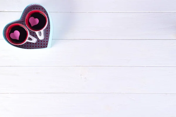 İki bardak kahve beyaz zemin üzerinde bir kalp şeklinde bir kutu içinde. Sevgililer günü kavramı, düz kopya alanı ile yatıyordu — Stok fotoğraf