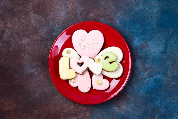 Vista dall'alto di biscotti a forma di cuore smaltato su piastra rossa isolata su pietra, posa piatta. Buon San Valentino — Foto Stock