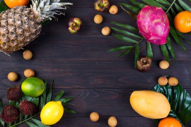 Tropikal meyve çerçeve koyu ahşap arka plan, düz yatıyordu kopya alanı üzerinde palmiye yaprakları ile