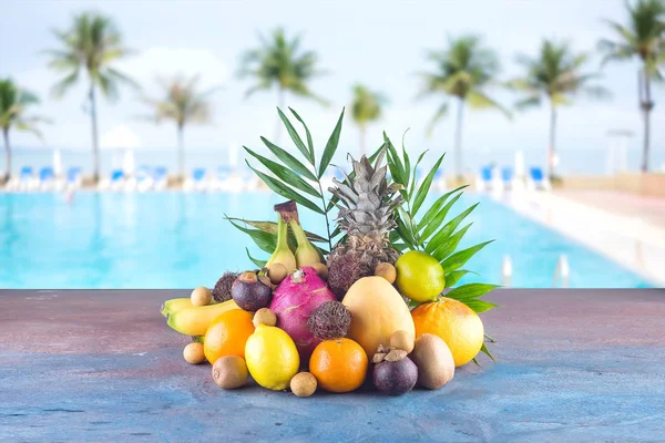 Assorted tropical fruits on the beach orange , pineapple, lime, mango, dragon fruit, orange, banan, rambutan and lichi Group of exotic tropical fruits.