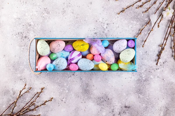 Huevos coloridos de Pascua pintados en colores brillantes con nido de paja en caja de madera sobre fondo de piedra, celebración de vacaciones de primavera, espacio para copiar —  Fotos de Stock