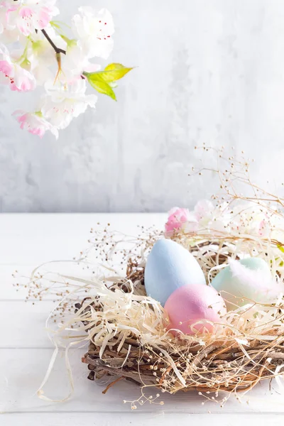 Piękny kwiat z kolorowych jaj w gnieździe na jasnym tle. Wiosna i Wielkanoc wakacje koncepcja kopia przestrzeń. — Zdjęcie stockowe