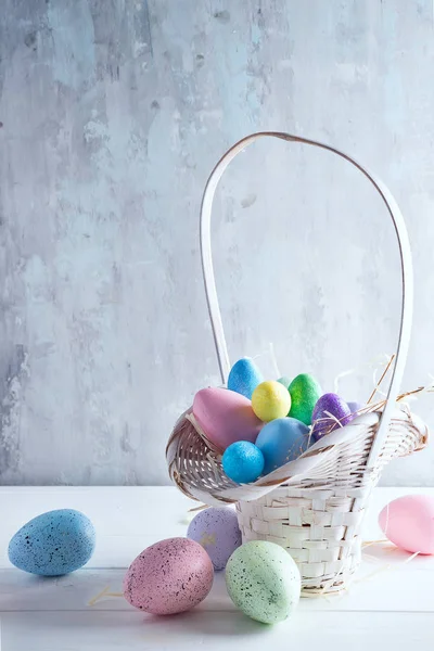 Pasen mand gevuld met kleurrijke handgeschilderde paaseieren op een lichte achtergrond — Stockfoto