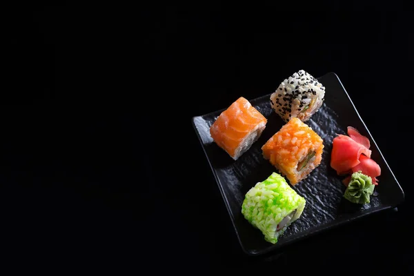 Large sushi sets with lots of sushi, roll . Stylish sushi sets on a black ceramic plane and table with Chinese sticks. Copy space