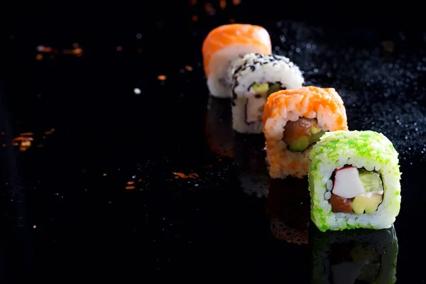 Colorful sushi sets with lots of sushi, roll . Stylish sushi sets on a black background with water drops . Copy space flat lay