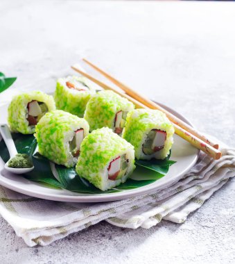 suşi, taş zemin üzerine yemek çubukları ile bir plaka üzerinde yeşil havyar ile rulo. Sushi menüsü. Japon yemekleri kopya alanı.
