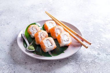 Philadelphia rulo klasik yemek çubukları ile bir tabakta. Japon suşi yiyecek