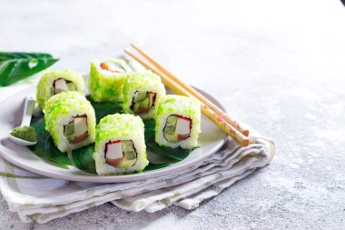 suşi, taş zemin üzerine yemek çubukları ile bir plaka üzerinde yeşil havyar ile rulo. Sushi menüsü. Japon yemekleri kopya alanı.
