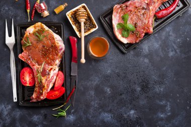 Taze çiğ et rosemary ile marine edilmiş baharatlı domuz eti, baharat ve otlar siyah arduvaz tabakta görmek yukarıda, pişmemiş kopyalama alanı