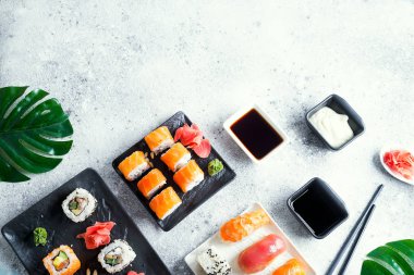 Siyah ve beyaz kayrak metal ve kayrak sopa, sos ve düz yatıyordu kopya alanı hafif taş zemin üzerine yeşil yaprakları ile ayarlamak çeşitli taze ve lezzetli suşi