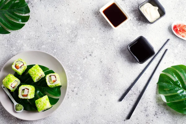 Rollo de sushi con caviar verde en un plato con palillos sobre fondo de piedra. Menú plano de Sushi lay. Espacio de copia de comida japonesa . — Foto de Stock