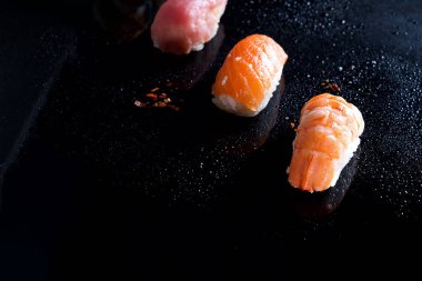 Sashimi, uramaki ve nighiri, pirinç, somon ve ton balığı, oluşan Japon yemek karides siyah su damla ile. Japon restoranı, düz kavramı kopya alanı yatıyordu
