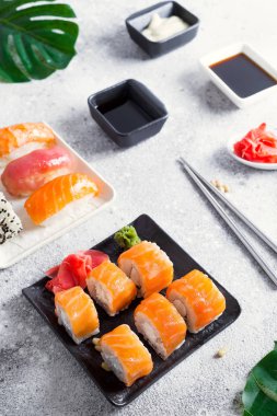 krem peynir Philadelphia chopsticks ve sos ile klasik bir taş siyah plaka üzerinde rulo. Japon suşi yemek. Kopya alanı